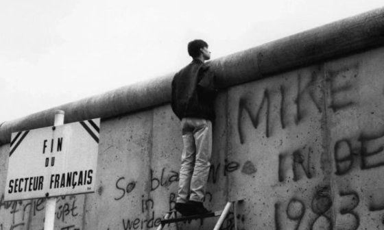 Muchacho asomado por encima del Muro de Berlín.