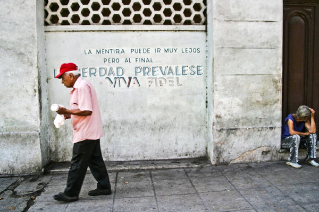 Calle de La Habana con consigna, anciano cruza