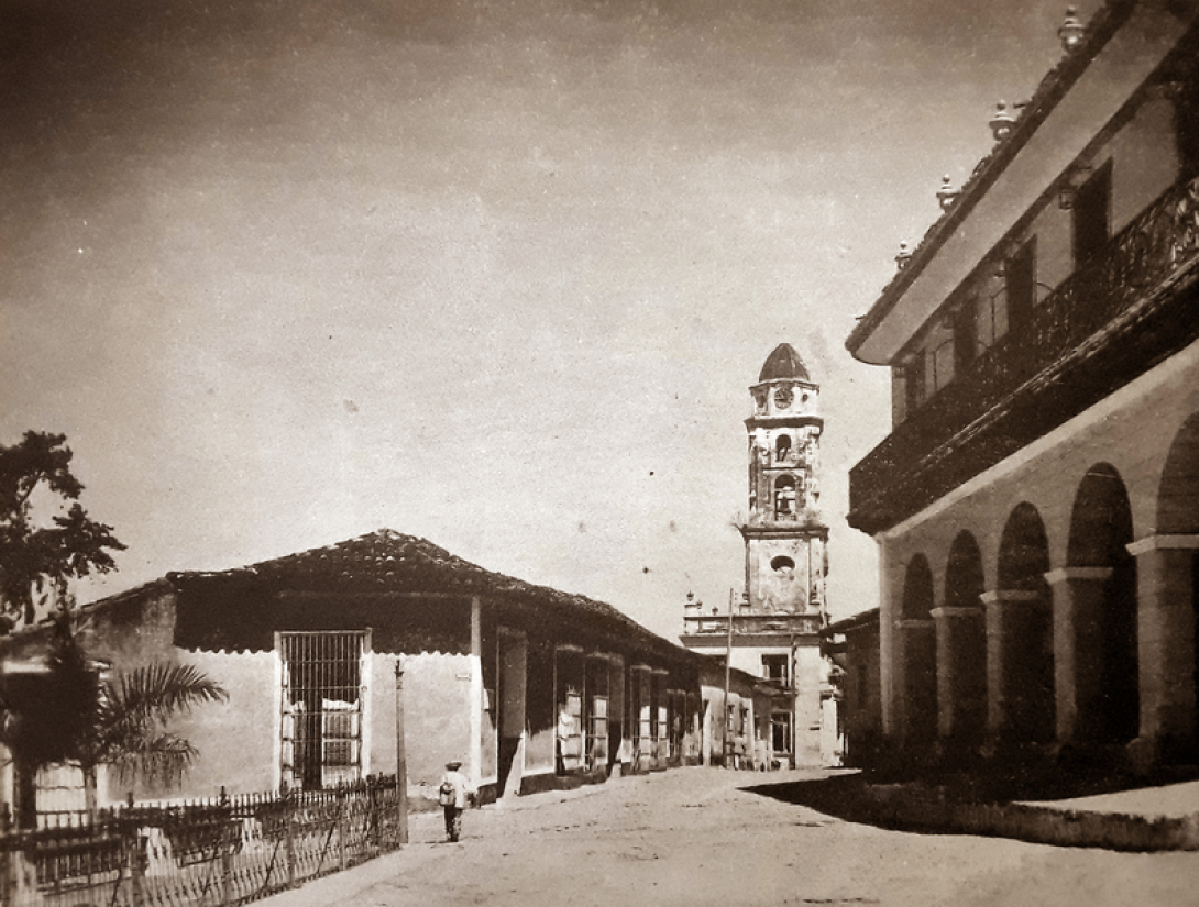 Foto antigua de la ciudad de Trinidad en Cuba: una calle que conduce al la torre insignia de la villa entre casonas coloniales.