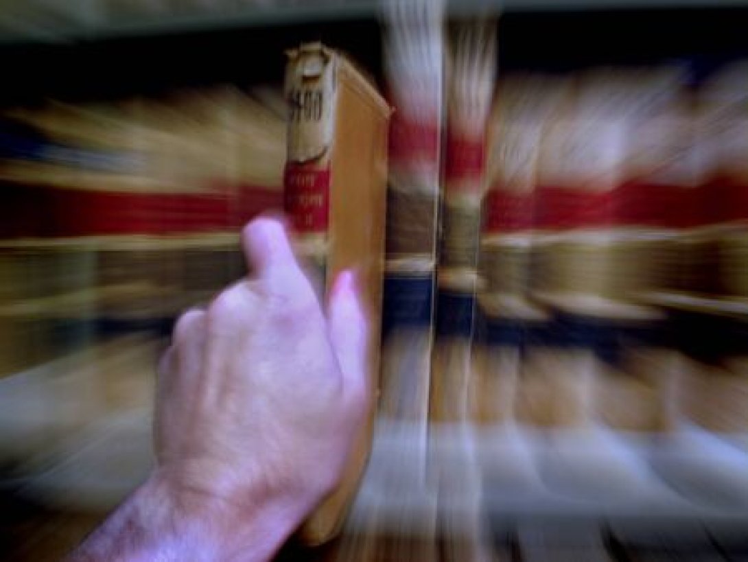 Una mano sacando libros de una estantería