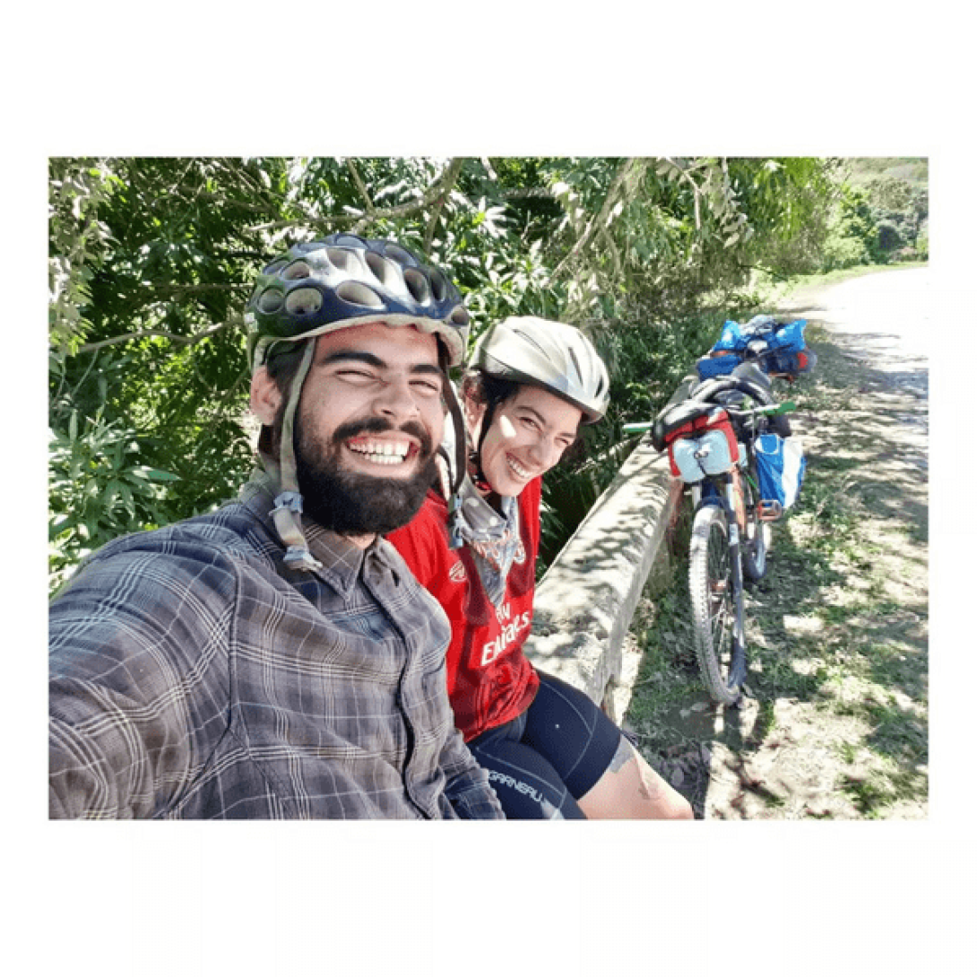 Yasnay y Miguel soriendo descansan junto a sus bicicletas.