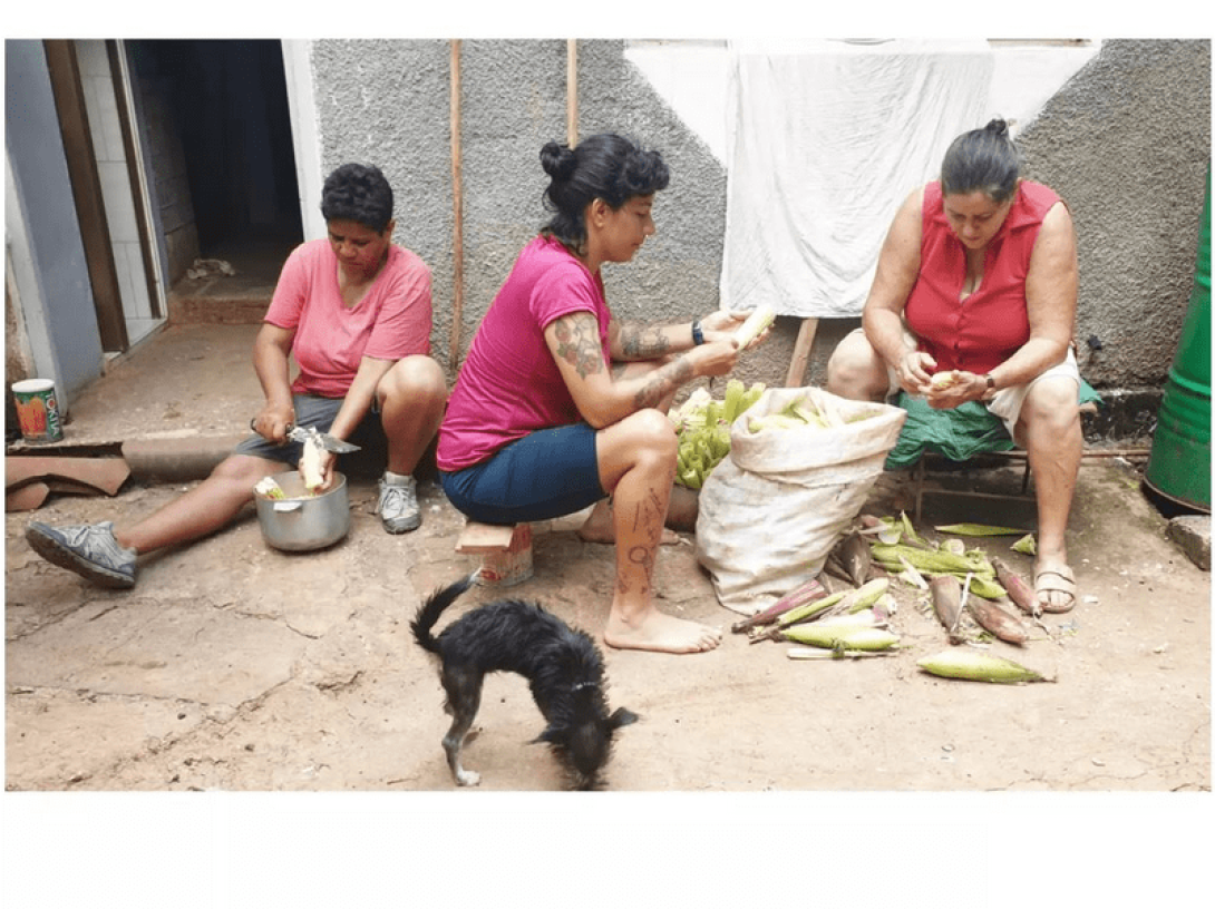 Tres mujeres sentadas preparando el maíz.