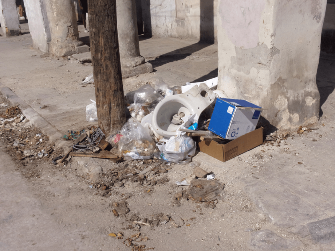 Basura acumulada junto a una edificación en la calle.