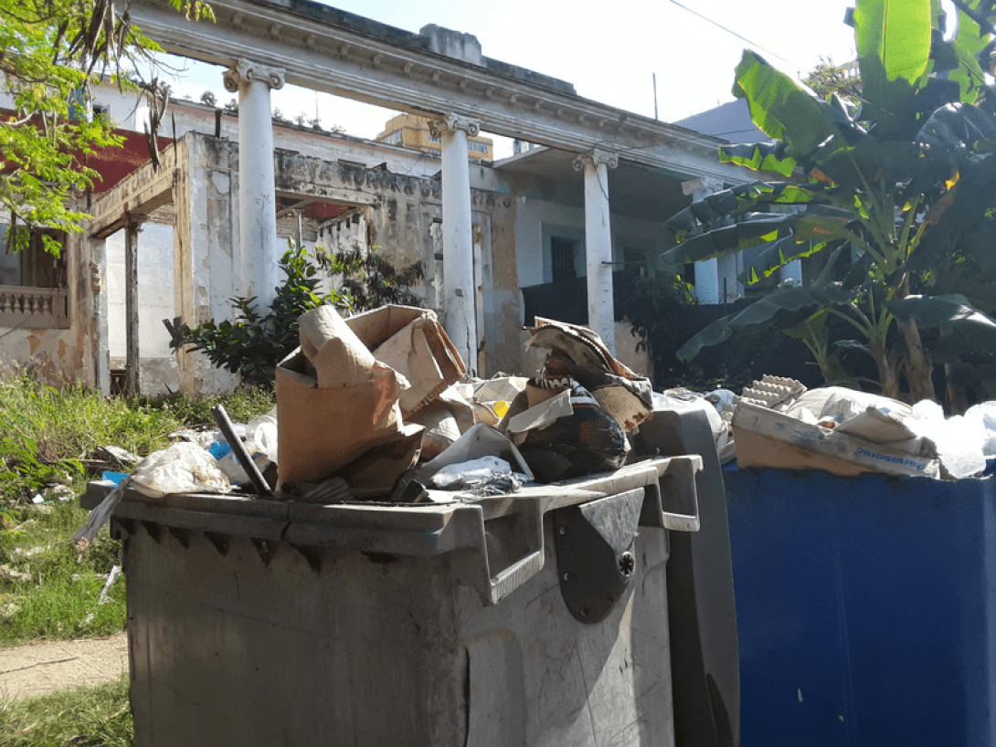 Contenedores de basura rotos y desbordados de desperdicios.