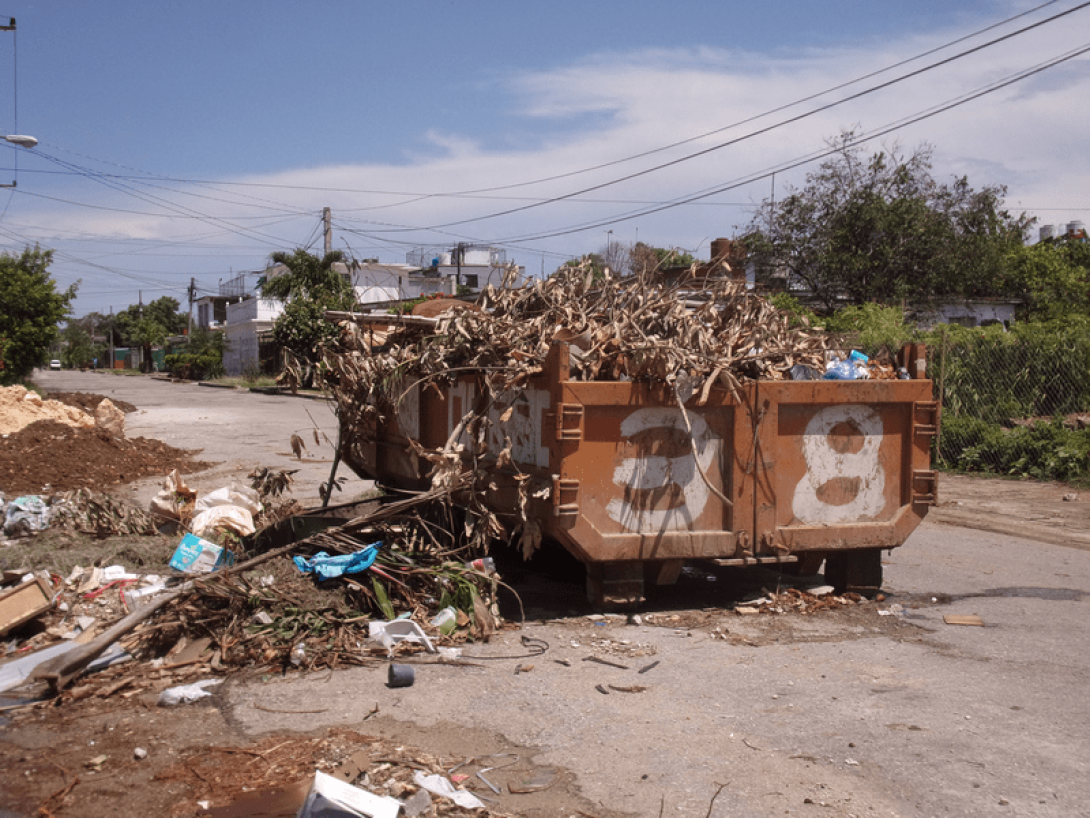 Contenedor de basura desbordado de desperdicios en la calle.