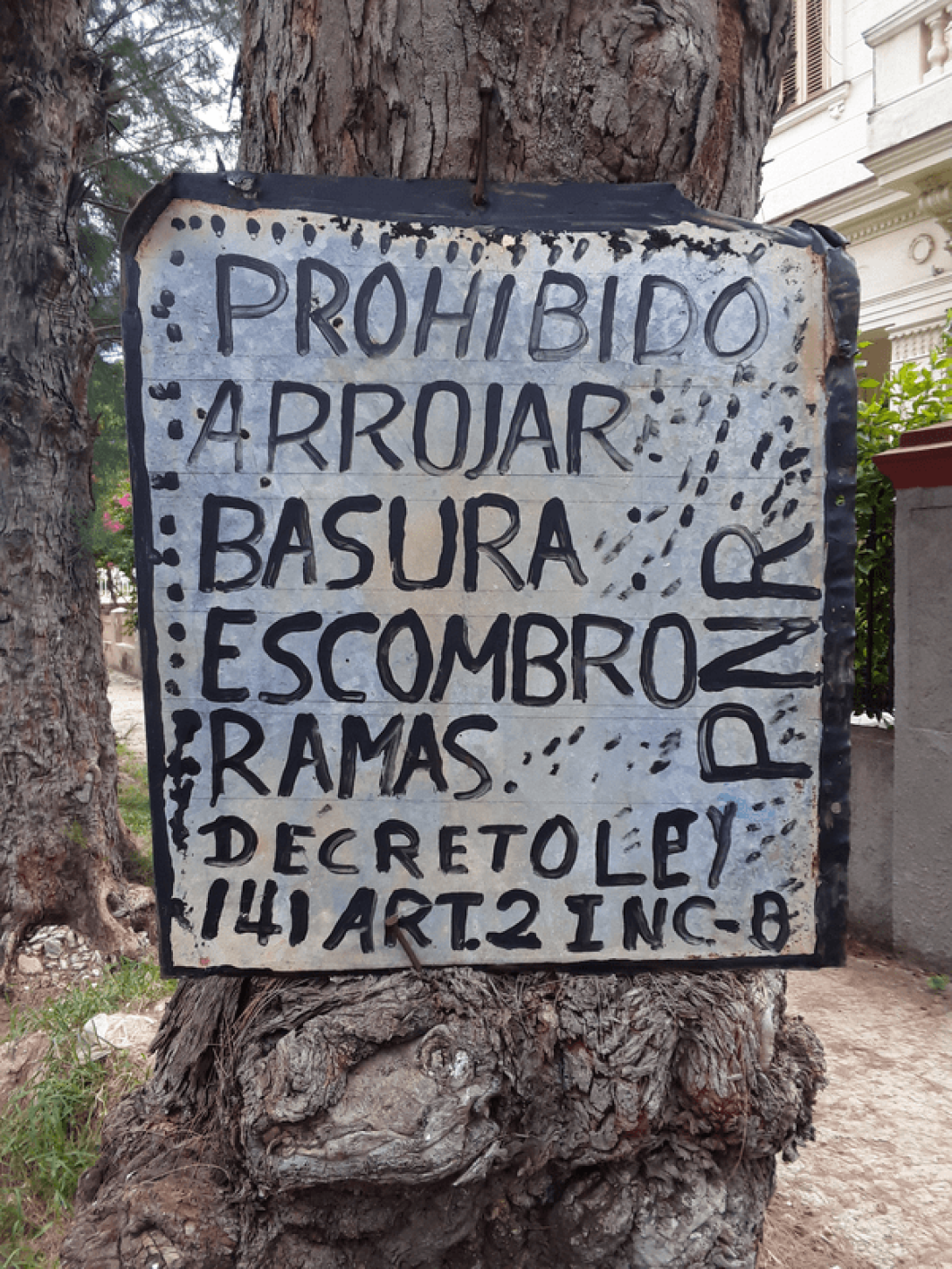 Cartel en un árbol: "Prohibido arrojar basura, escombro..."