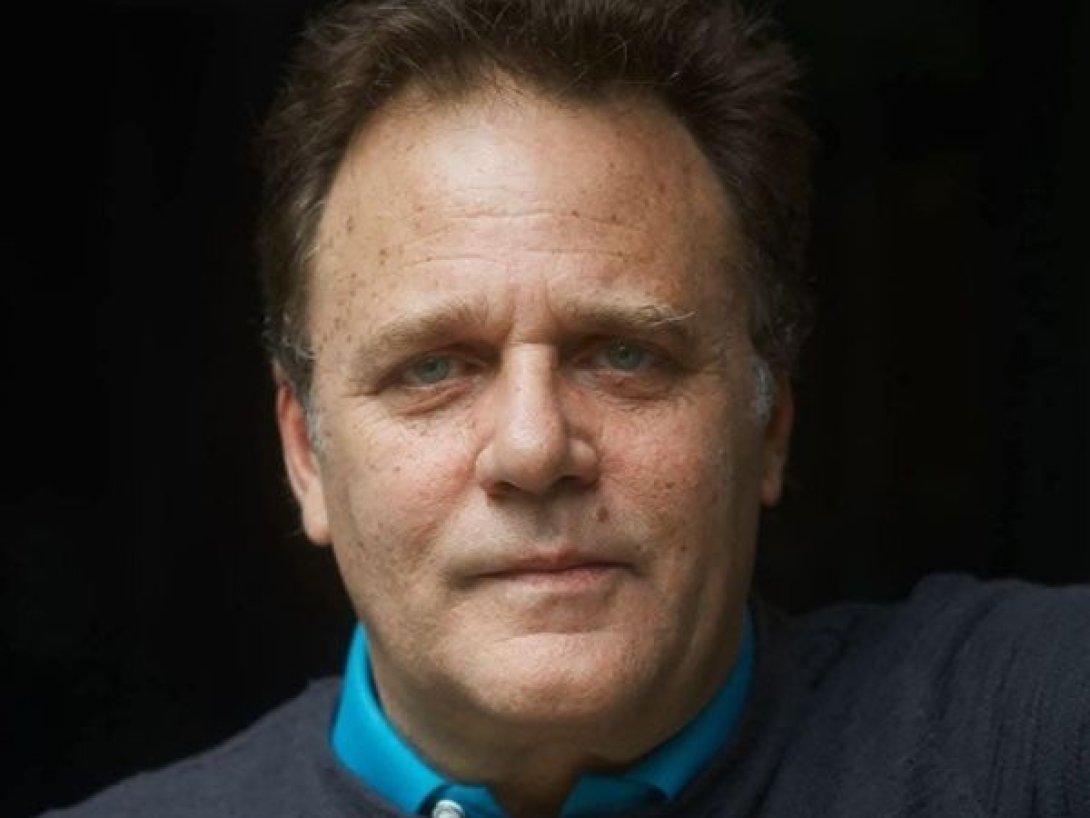 Retrato de Mauricio Rentería, actor y director de teatro, mirando a cámara, plano medio con fondo oscuro.