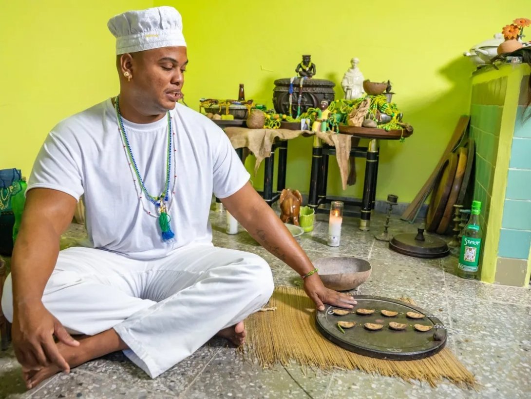 Babalawo cubano durante una consulta de Ifá con el ékuele, cadena cuyas ocho piezas de coco forman al caer uno de los signos u odù interpretados por el sacerdote.