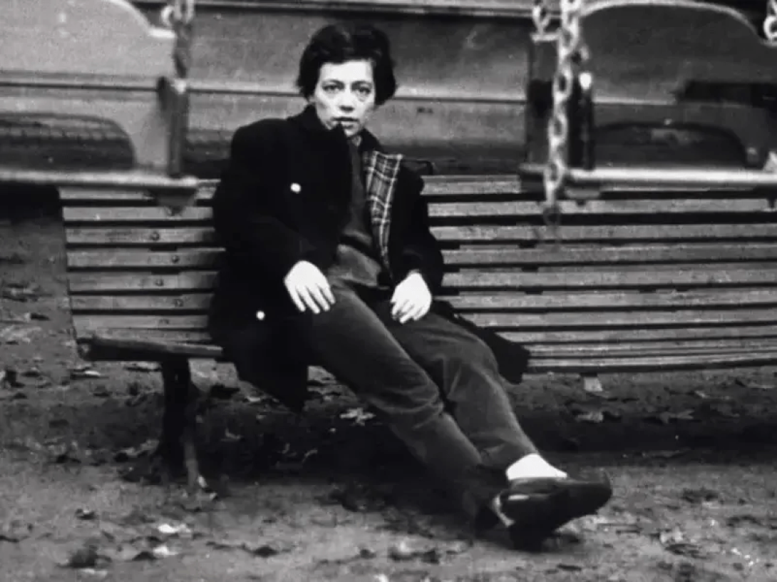 Retrato de Alejandra Pizarnik sentada en un banco.