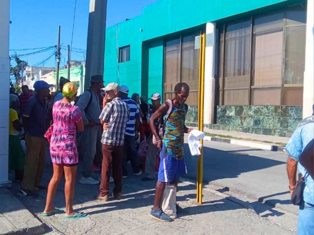 Jubilados de Santiago de Cuba haciendo cola a la sombra exterior de un banco de la ciudad para extraer dinero en efectivo (abril de 2026).