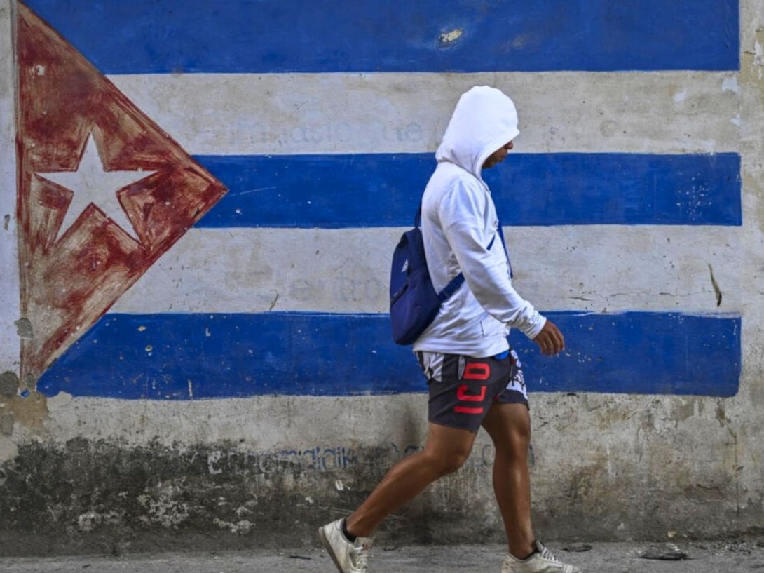 Una persona caminando frente a una bandera de Cuba pintada en un muro de La Habana el 22 de marzo de 2026. Foto de Yamil Lage (AFP).