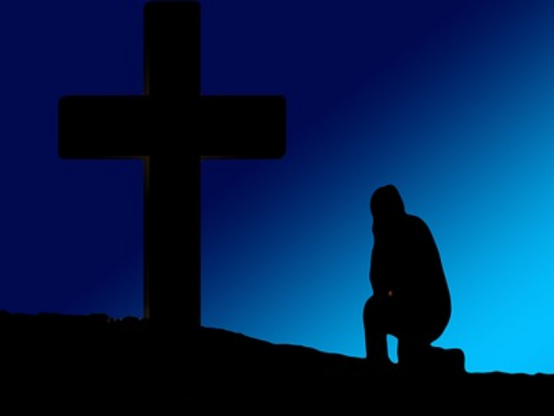 Figura humana reclina su rodilla ante la cruz (cristiana).