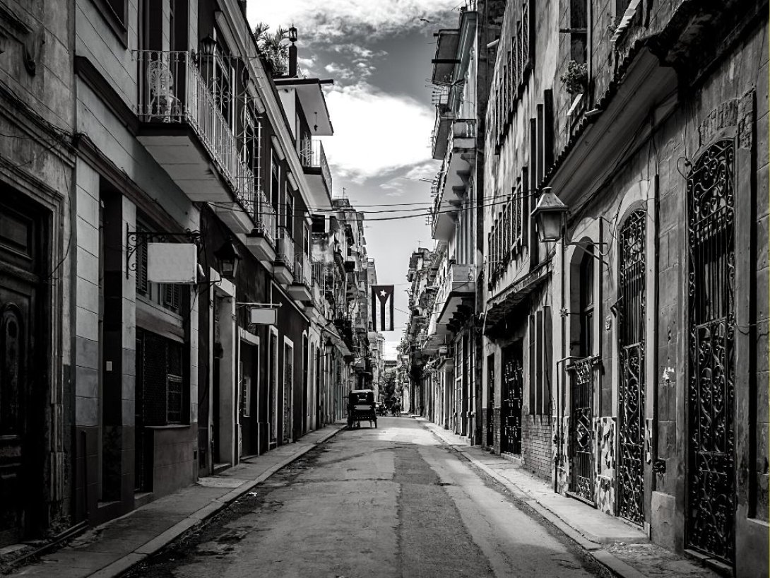 Calle en Cuba con una bandera cubana colgada al centro.