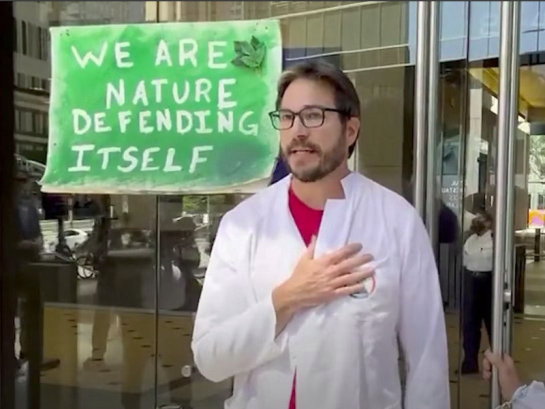 Científico protestando junto a un cartel (en inglés): "somos la naturaleza defendiéndose a sí misma".