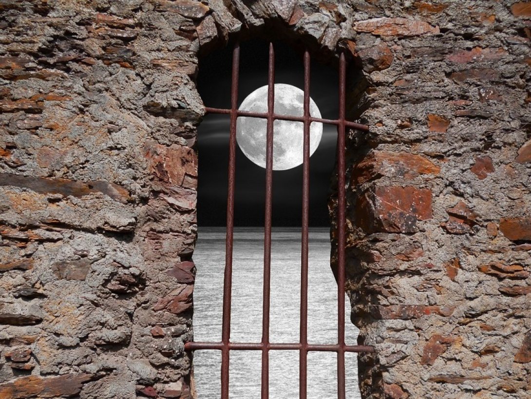 Una luna llena sobre el mar a través de las rejas de una cárcel.