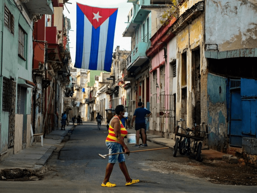 Calles de Cuba: pobreza, basura y una bandera cubana colgada en el centro.