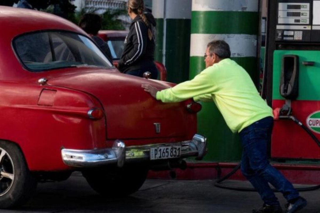 Cubano empuja su auto en una gasolinera.