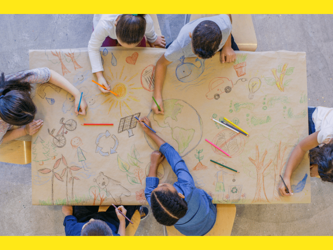 Niños pintando en una mesa dibujos que reflejan el cuidado del medio ambiente.