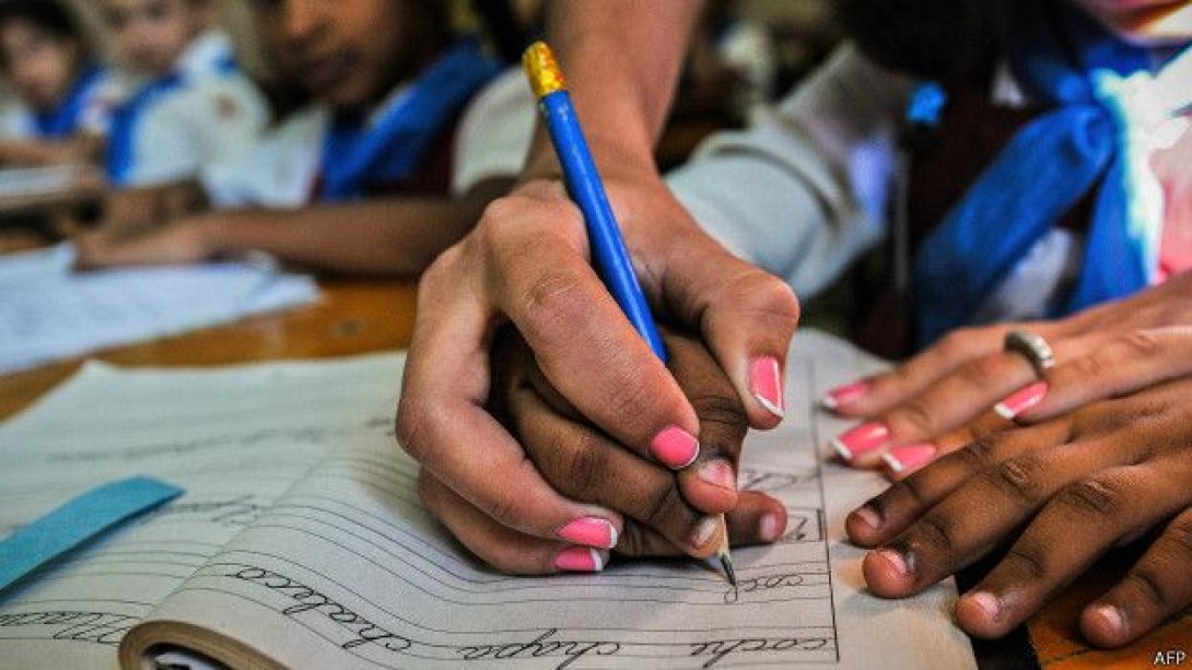 Maestra enseña a un niño cubano a escribir