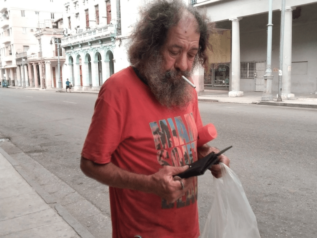 Persona fuma un cigarro en las calles de La Habana mientras mira un celular...