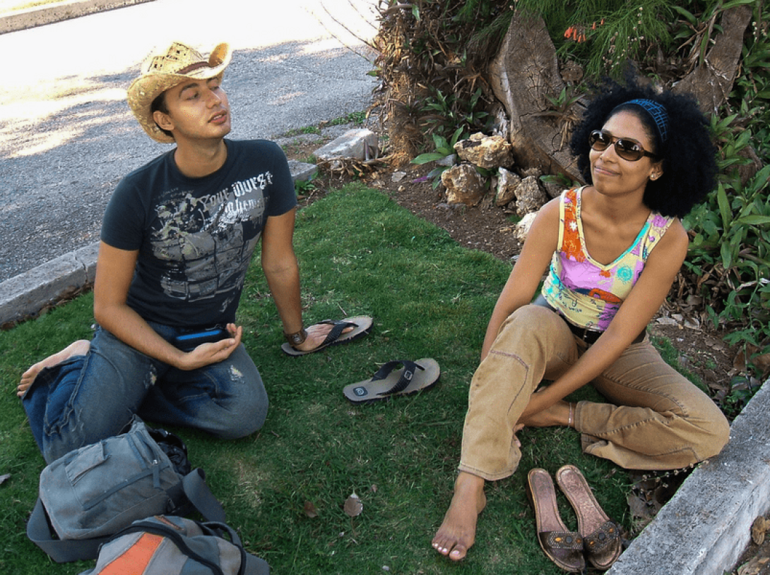 Dos personas sentadas en la yerba.