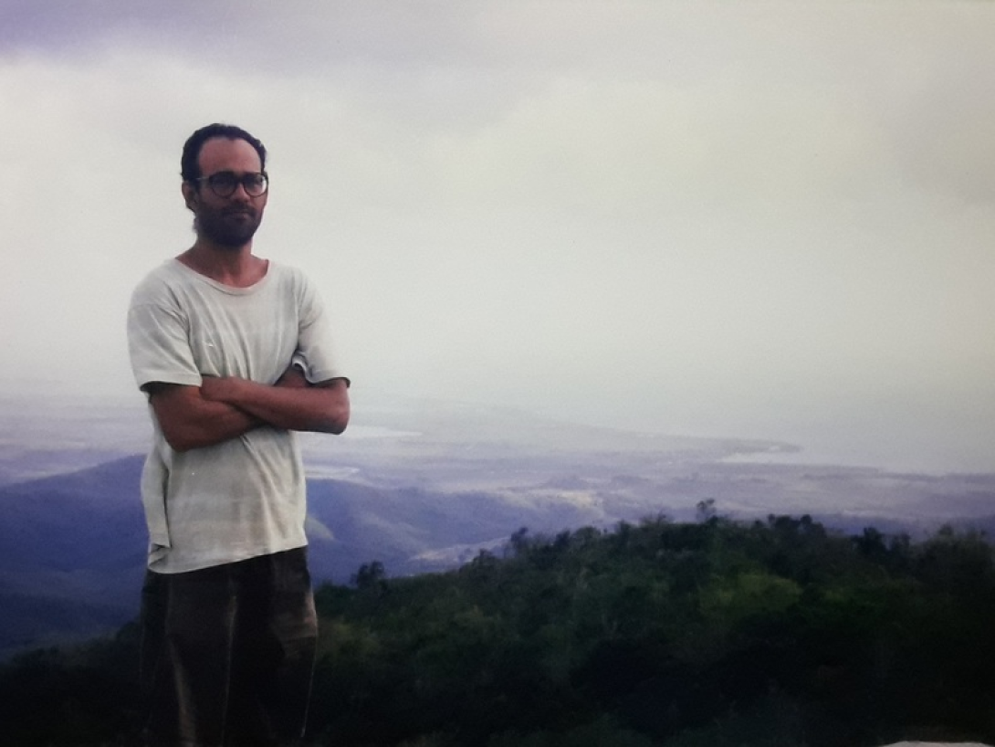 Amilkar posando delante de un paisaje de montañas y nubes.