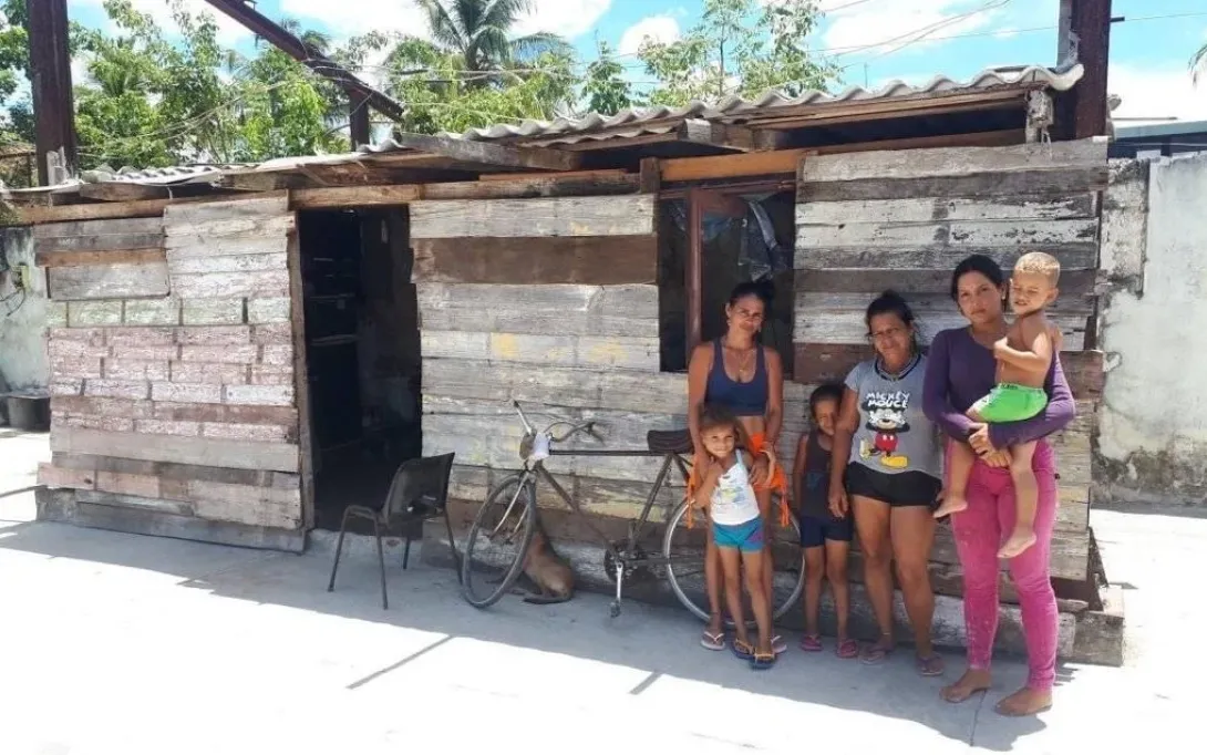 Familia cubana junto a una vivienda precaria.