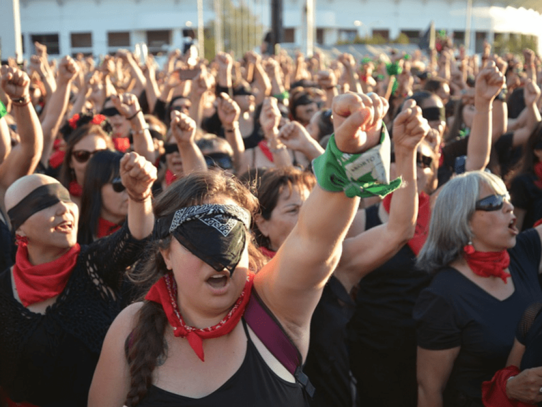 Feministas latinoamericanas protestando con pañuelos negros y verdes y levantando puños.