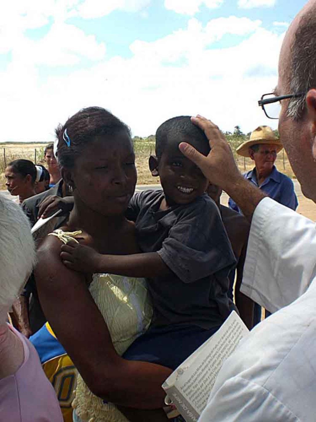Sacerdote bendice a un niño en el campo. Foto: Ferriol Grasso