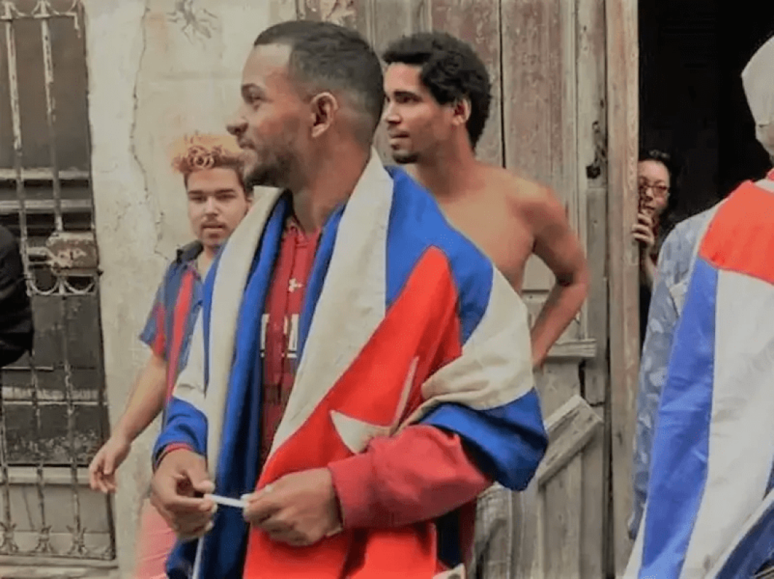 Personas en la calle con una bandera cubana. 