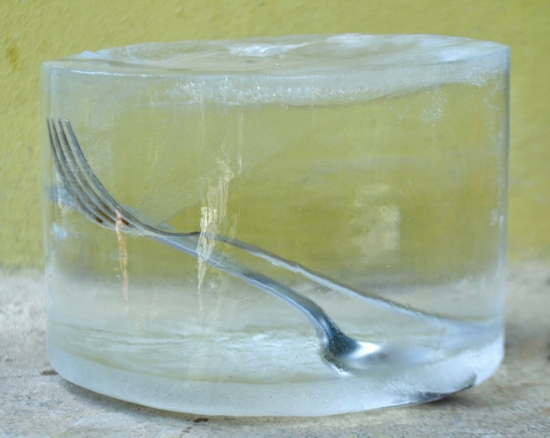 Un tenedor y una cuchara dentro de un bloque de hielo.