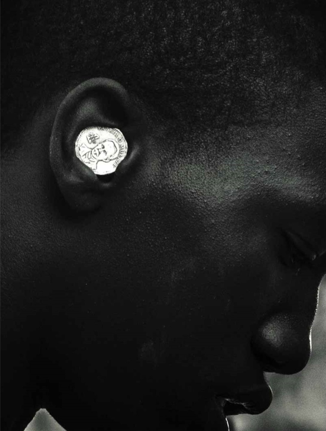 Niño negro con moneda de 1 peso en la oreja. Foto país de píxeles