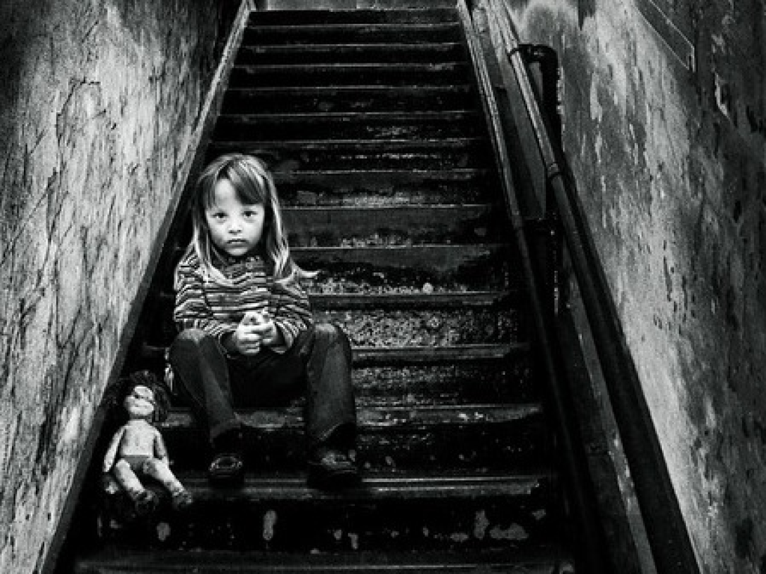Niña sentada en una escalera junto a su muñeca.