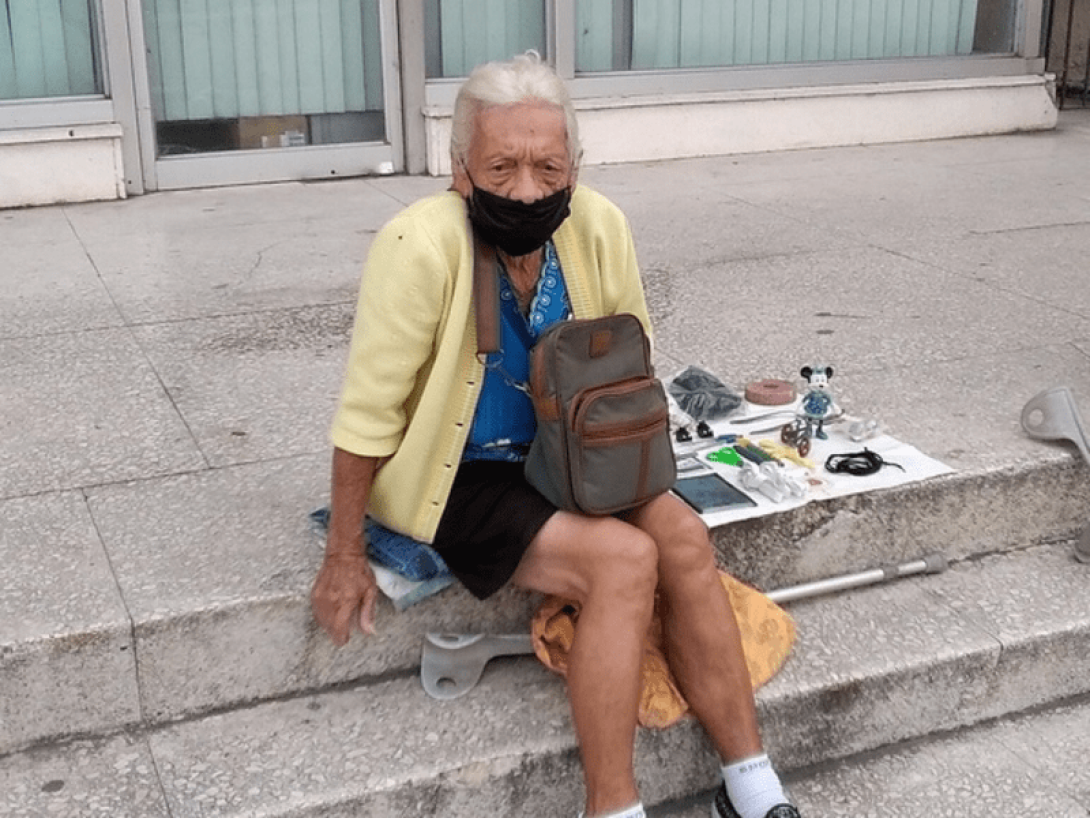 Mujer anciana en Cuba vendiendo artículos variados.