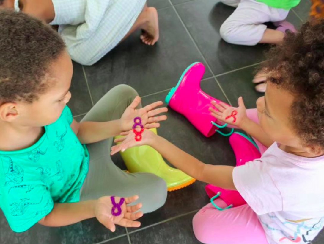 Dos niños interactúan sentados en el piso.