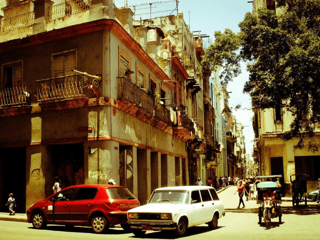 Vista de una calle de Cuba con autos y edificios antiguos.