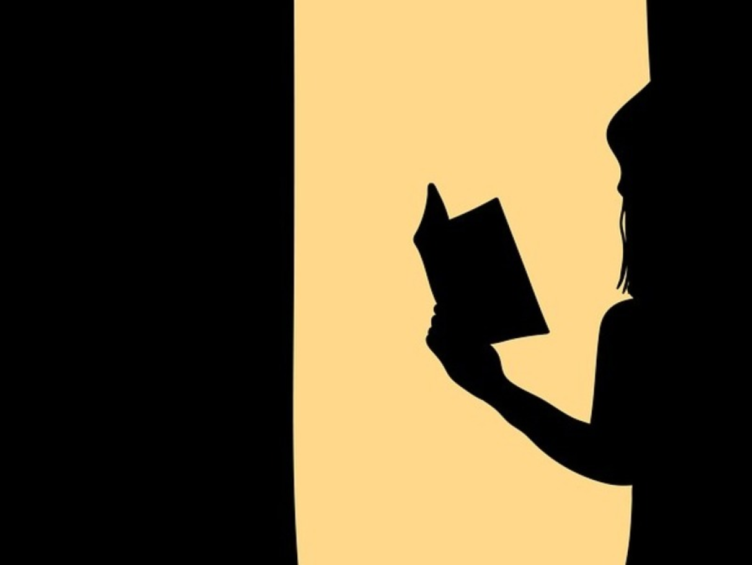 Silueta de mujer leyendo un libro.