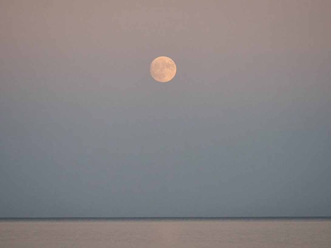 Luna llena sobre el mar en la tarde.