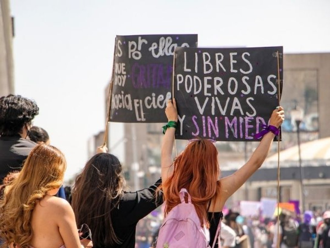 Mujeres jóvenes levantan pancartas en una manifestación feminista con consignas contra el machismo y el feminicidio en América Latina.