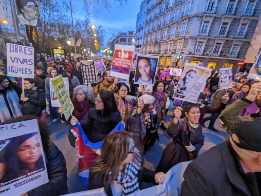Cubanas y cubanos sostienen carteles con los rostros de las prisioneras políticas en la manifestación del 8M en Madrid.