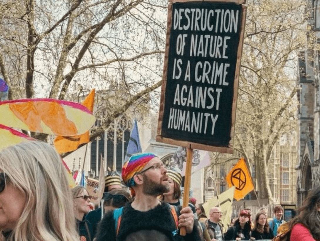 Activista sosteniendo un cartel donde se lee: "Destruction of nature is a crime against humanity" (la destrucción de la naturaleza es un crimen contra la humanidad).