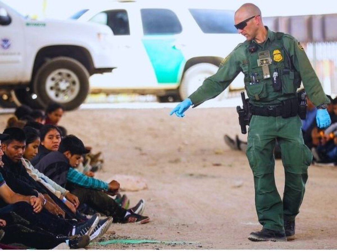 Agente de la Patrulla Fronteriza de Estados Unidos supervisa a un grupo de migrantes detenidos en la frontera con México.
