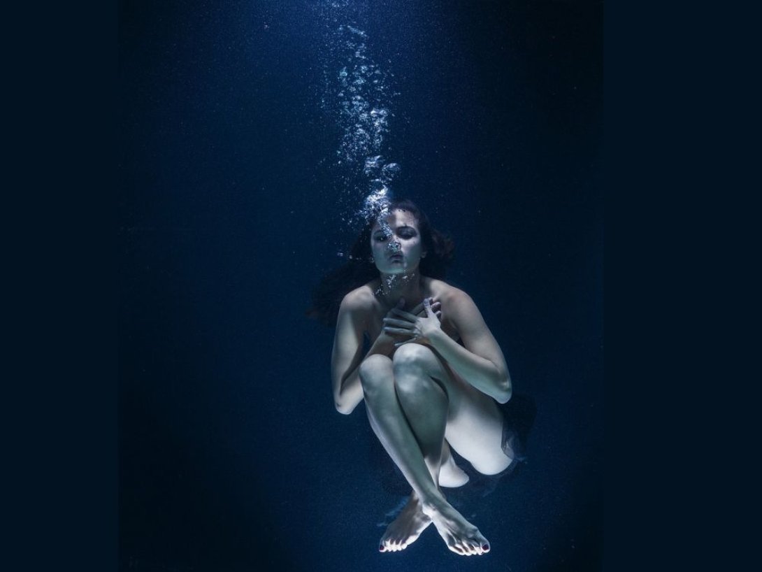Mujer desnuda sumergida en el agua.