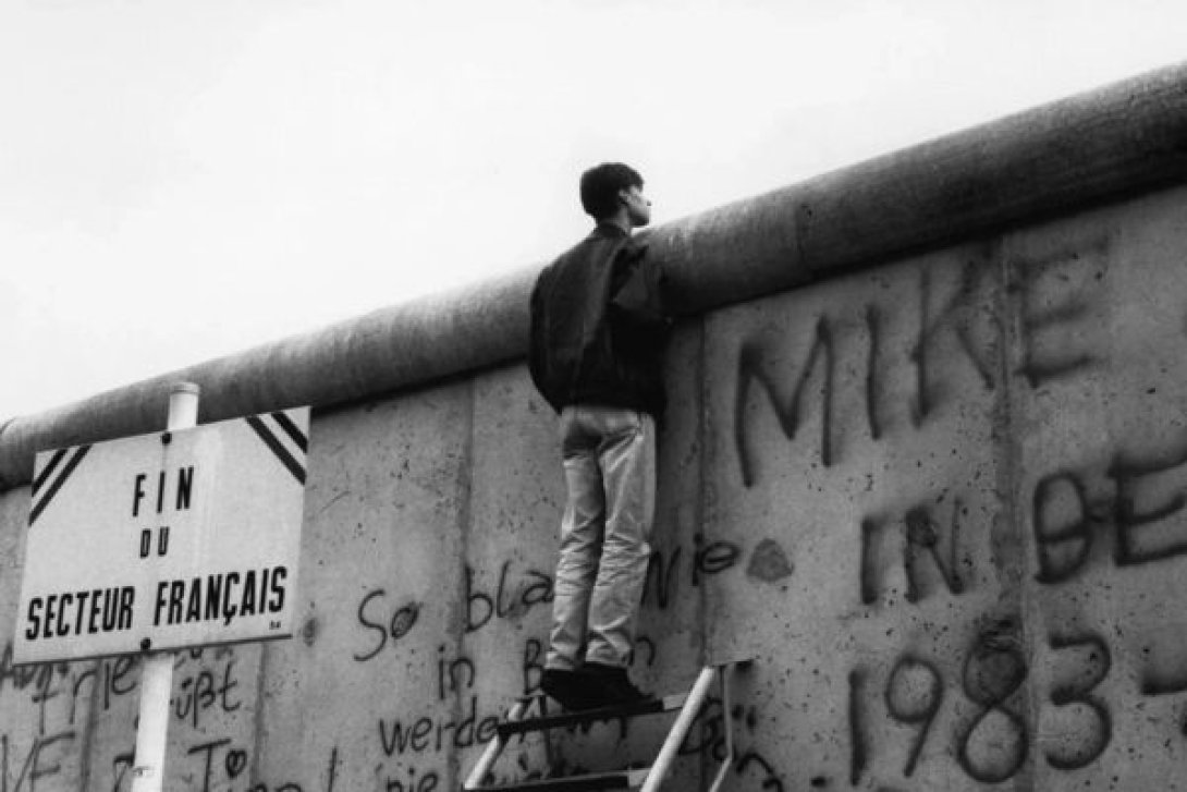 Muchacho asomado por encima del Muro de Berlín.