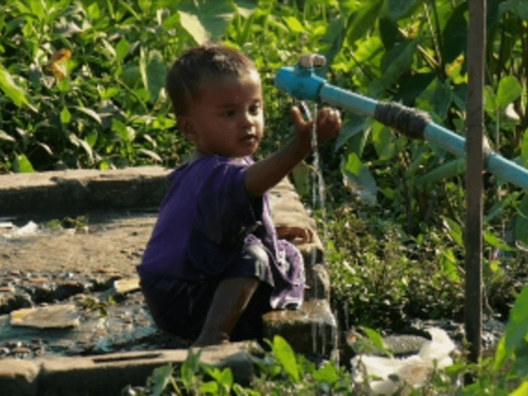 Niño tomando agua en la selva durante el cruce del Tapón del Darién, en Latinoamérica.