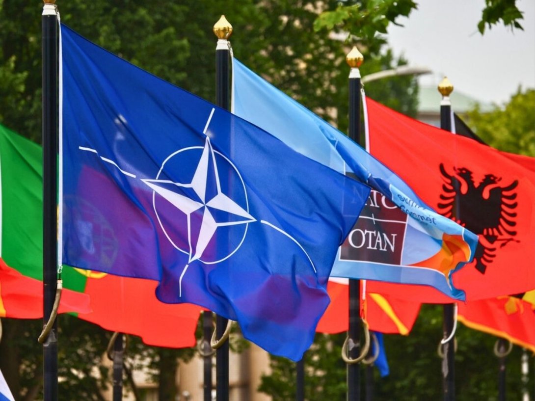 Bandera de la Organización del Tratado del Atlántico Norte (OTAN) ondeando junto a banderas de algunos países miembros.