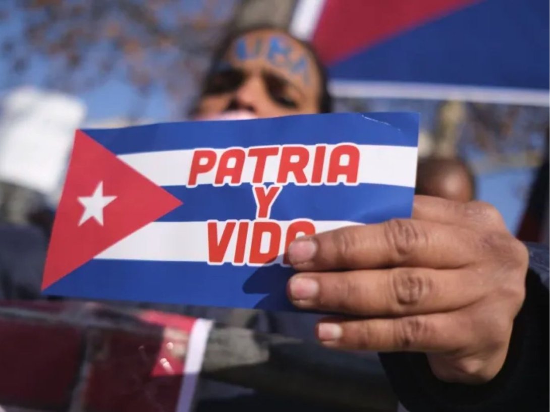 Cubana sosteniendo una bandera cubana con el lema "Patria y Vida".