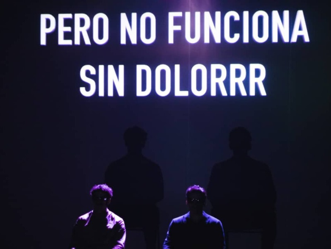 Cartel proyectado en el teatro sobre dos actores: "Pero no funciona sin dolorrr", durante la puesta en escena de "Normalización".