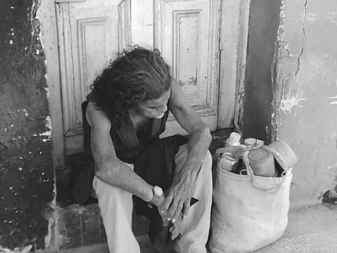 Una mujer sentada delante de una puerta con expresión de cansancio.