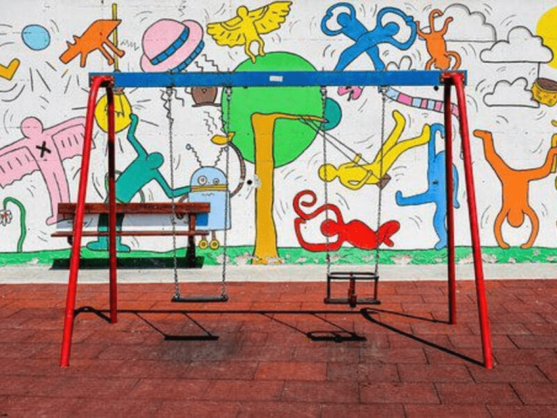 Columpios con pared grafiteada detrás.